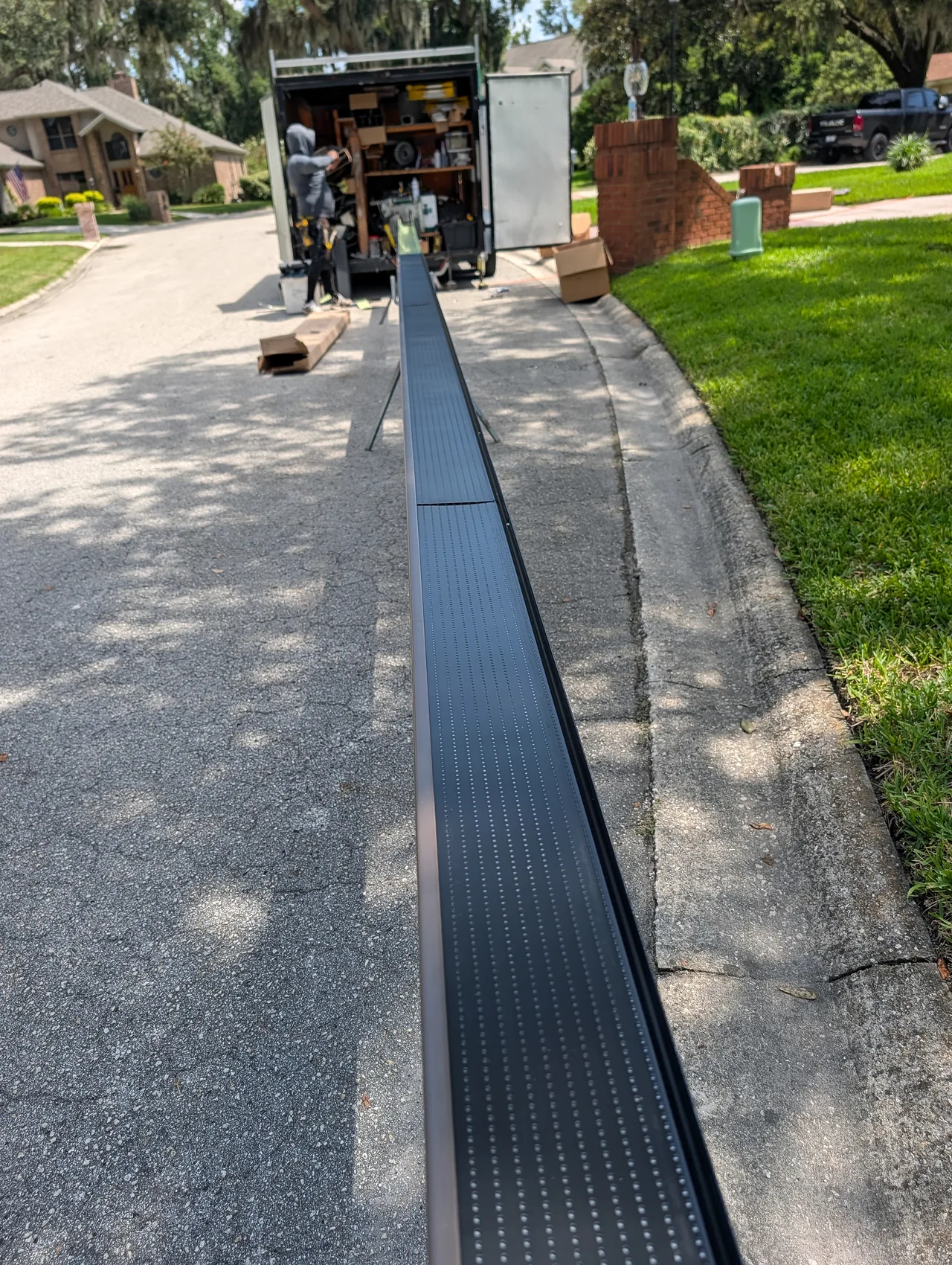 Clean Gutter Protection gutter sections being prepared on stands beside the crew vehicle